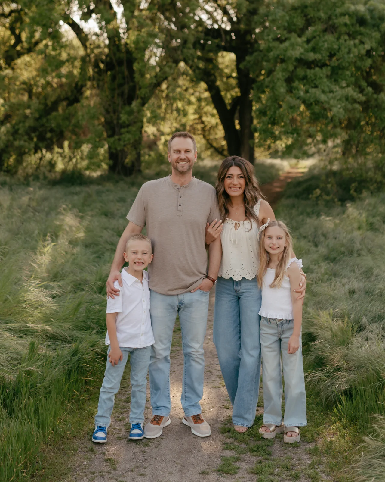 Dr. Becker and his family posing together on a dirt path in a grassy field